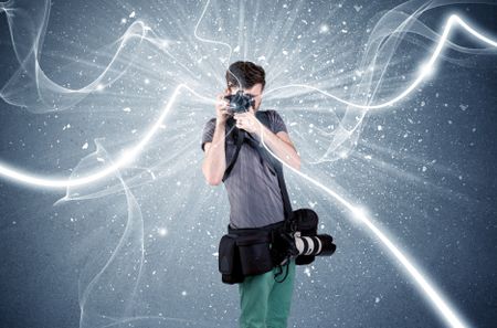 A young amateur photographer with professional photographic equipment taking picture in front of blue wall with dynamic white lines illustration concept