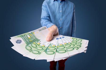 Young businessman holding large amount of bills 