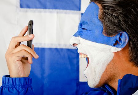 Angry man calling Greece and yelling with the flag painted on his face