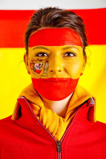 Patriotic Spanish woman with the flag behind her and paint on her face