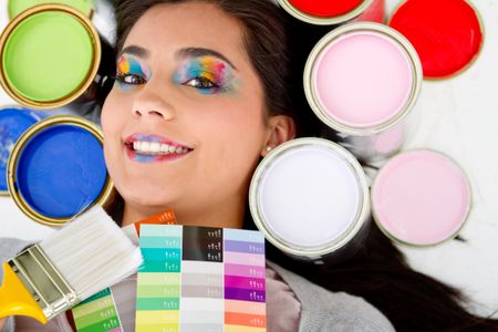 Female painter smiling with paint cans in different colors aroun her head