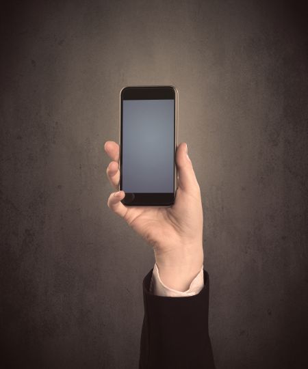 Caucasian hand in business suit holding a blank screen smartphone
