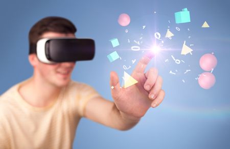 Young impressed man wearing virtual reality goggles with geometric shapes around his hand