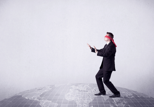 Young blindfolded businessman steps on a grey world map