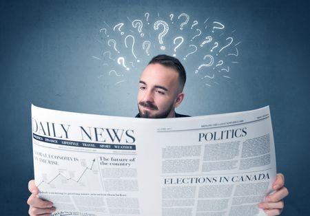 Young confused businessman reading daily newspaper with question marks above his head
