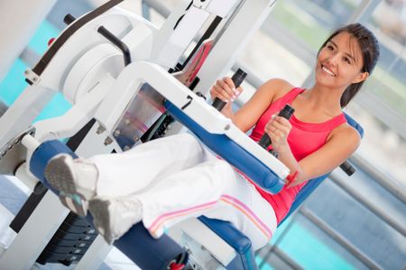 Woman exercising her arms and back at the gym on a machine