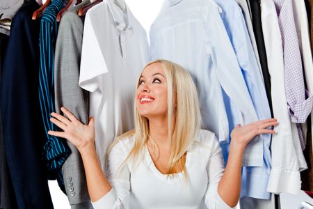 Overwhelmed woman picking clothes and sitting in a wardrobe