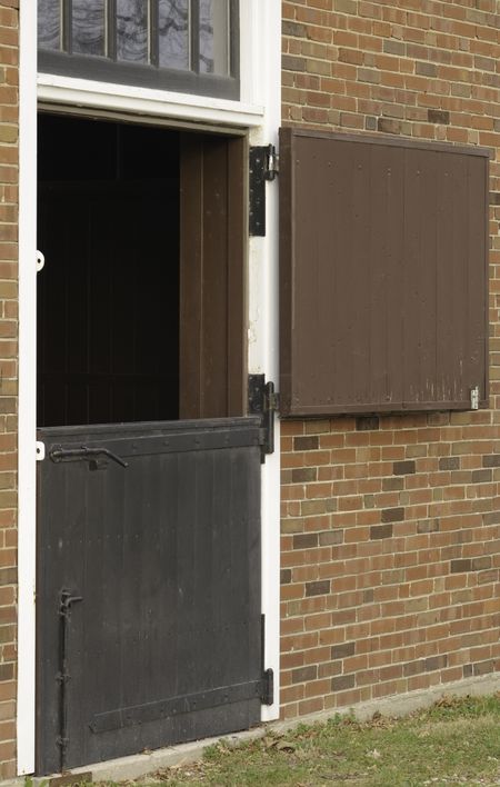 Dutch door to Colonial-style brick horse stable, with top half open