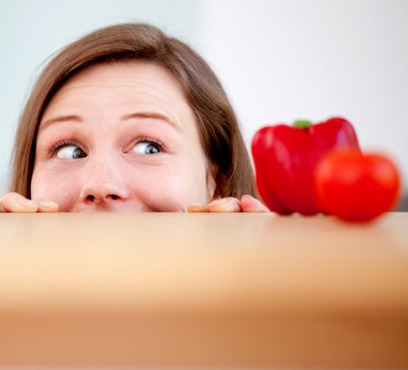 Woman in the kitchen peeking at fresh food on a table