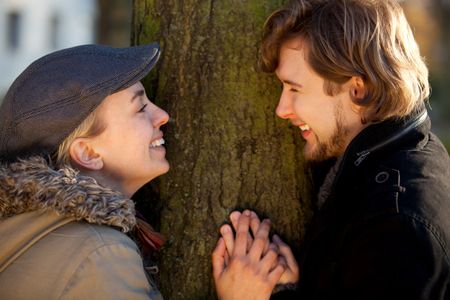 Portrait of a romantic couple outdoors behind a tree
