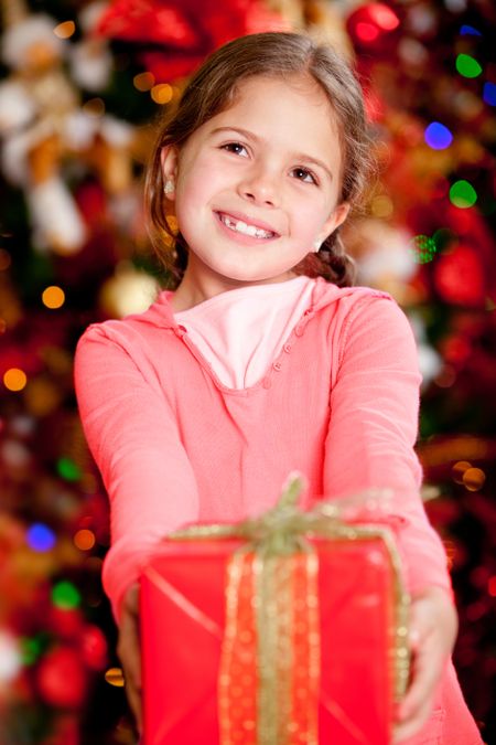 Beautiful girl holding a Christmas gift and smiling at home
