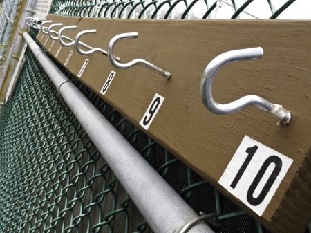 No waiting: Row of empty hooks for tennis rackets of players waiting to play on outdoor court