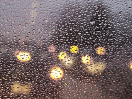 Abstract of rain at rush hour: Raindrops all over windshield (selective focus)