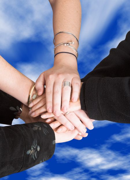 business team with their hands together with a sky on the background