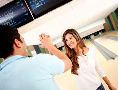 Happy couple winning at bowling and giving a high-five