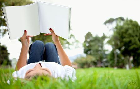 Woman lying down outdoors reading a book