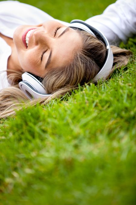 Girl lying at the park relaxing with music