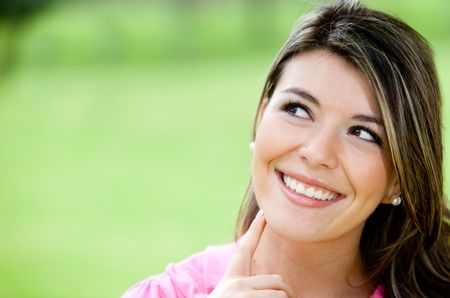 Portrait of a pensive young woman outdoors smiling