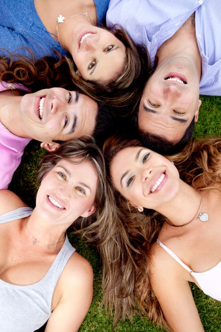 Friends lying down outdoors in a circle and smiling