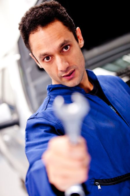 Male mechanic holding a wrench to fix a car