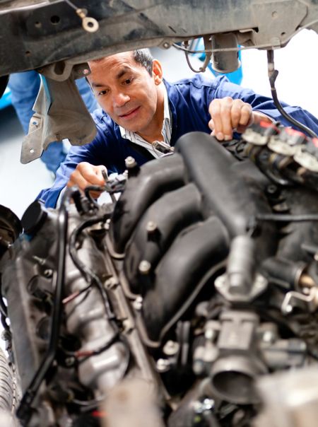 Male mechanic at a garage fixing a cars engine