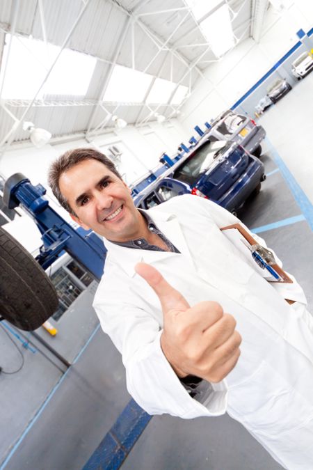 Male mechanic with thumbs up at a car garage