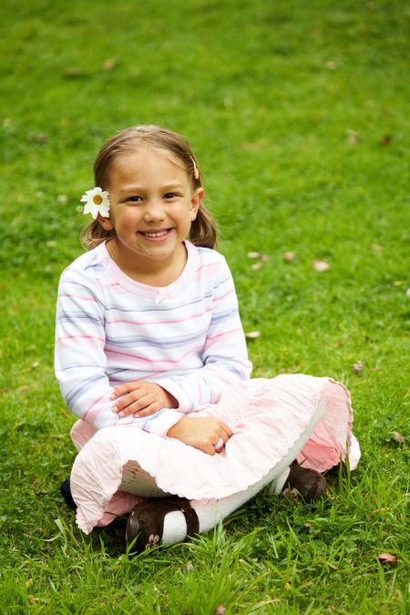 cute little girl portrait outdoors smiling sitting on the grass
