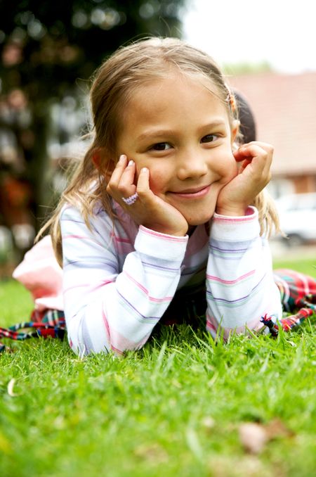 cute little girl portrait outdoors lying on the grass
